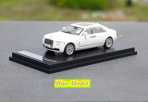 White alloy diecast car model on black display base, detailed 4-door sedan