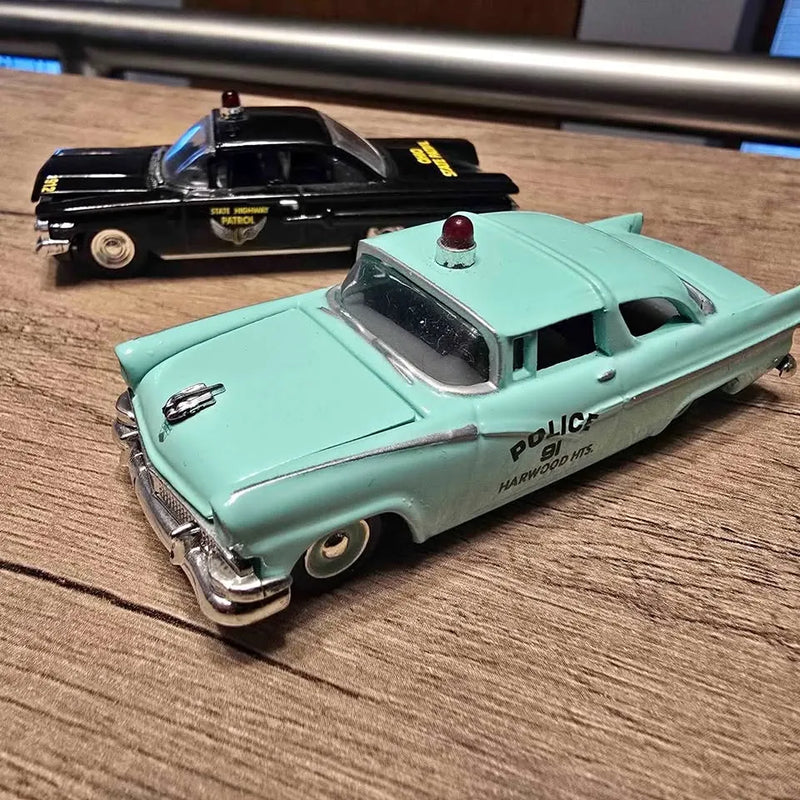 Turquoise diecast police car with roof lights and black hood, front three-quarter view