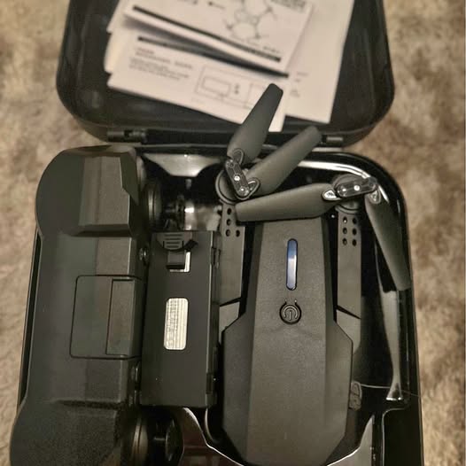 Mini drone in open carrying case with four propeller arms and controller panel
