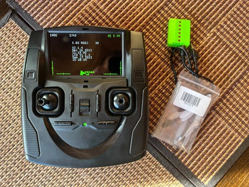 Gray FPV drone remote controller with screen and two joysticks, green battery pack