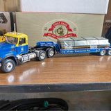 Diecast lowboy semi truck with pipe trailer load, blue cab, detailed metal finish