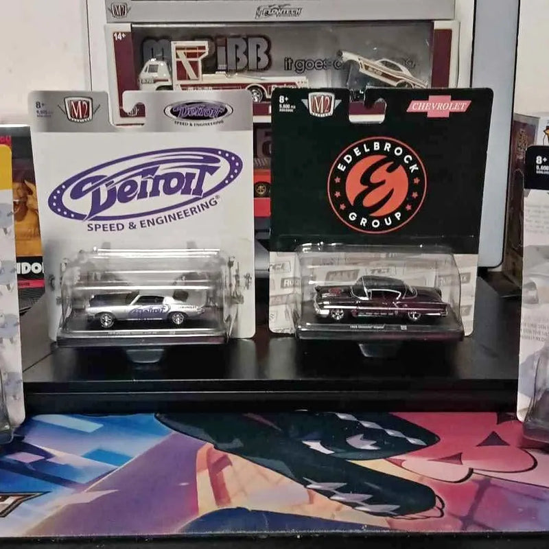 Two boxed M2 diecast race cars in clear blister packaging, front view