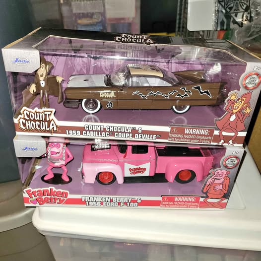 Diecast toy vehicle set in clear box, featuring a brown coupe and pink truck