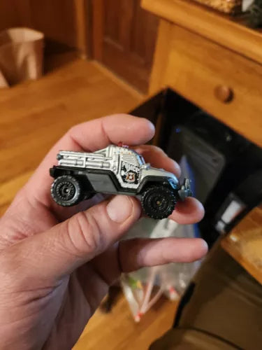Silver and black police toy diecast truck with detailed decals, side view.
