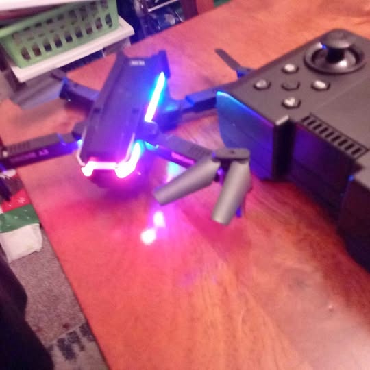 Small quadcopter drone with glowing LED lights and four propeller arms