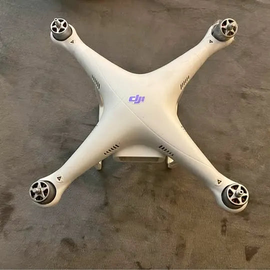 Broken DJI Phantom 3 quadcopter drone body with four propellers, no battery installed