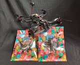 FPV racing drone with spare blade packs; red and black frame, four propellers