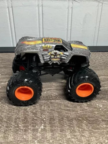 Black monster jam toy diecast truck with orange wheels, front view, 1:64 scale