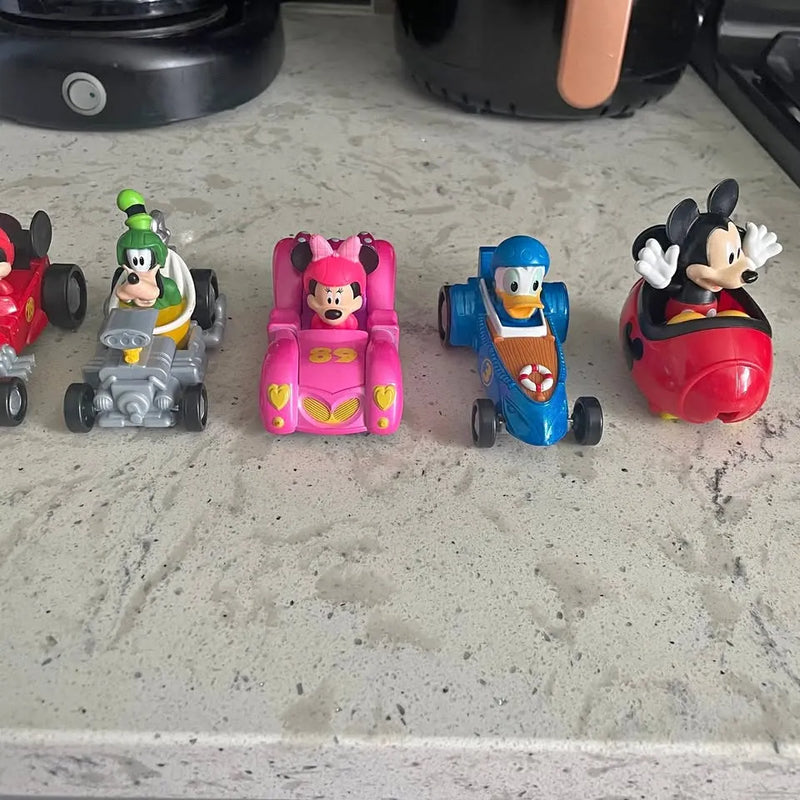 Four Disney Junior character diecast cars: gray, pink, blue, and red with faces