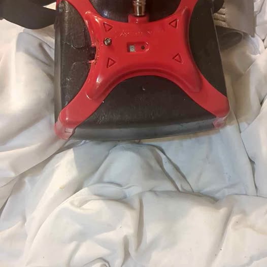 Red plastic drone frame with triangular cutouts and metal connectors on white fabric