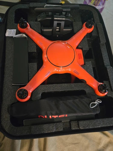 Orange quadcopter drone with 4 rotors, inside black carrying case