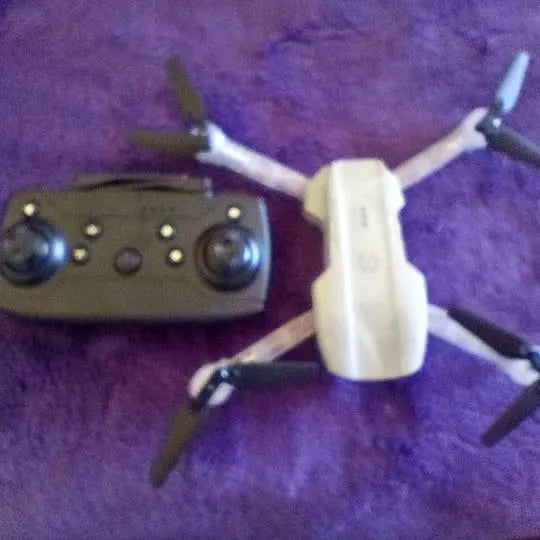 Handheld drone controller with black body, dual joysticks, and four circular control buttons