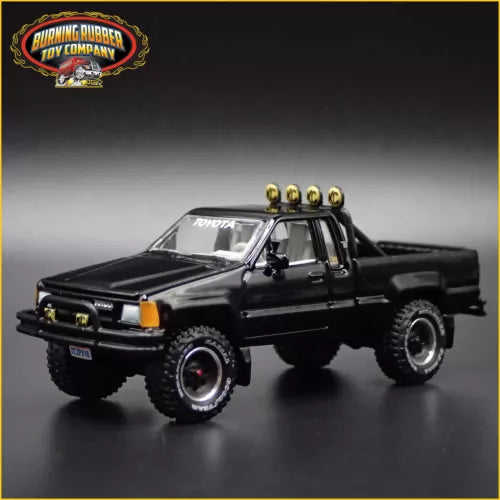 Black 1:64 diecast pickup truck model, front three-quarter view, off-road tires and light bar