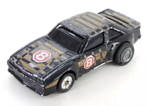 Vintage diecast toy rally car, black with gold stripes and number 8 decals, hood closed