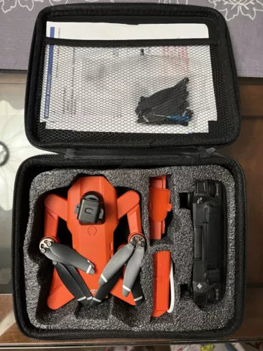 Four-axis drone set in black hard case, showing orange body, blades, and battery