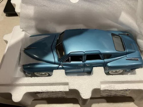 Blue 1:24 diecast model car with black hood and grille, inside protective box