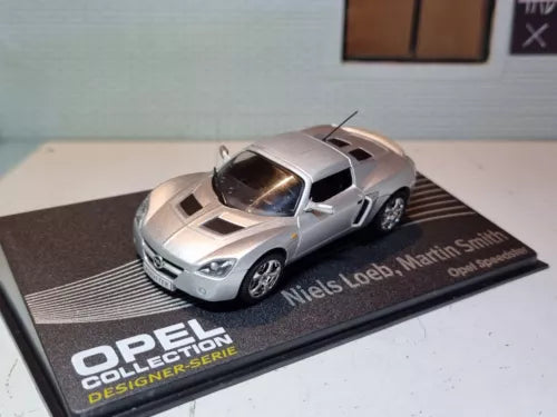 Silver diecast scale model sports car on branded display base
