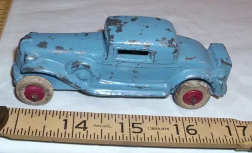 Light blue diecast toy coupe car with red wheels and visible wear
