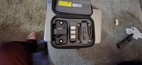 Foldable video drone kit in open case with controller and spare parts.