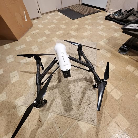Quadcopter drone with white body and four black propeller arms