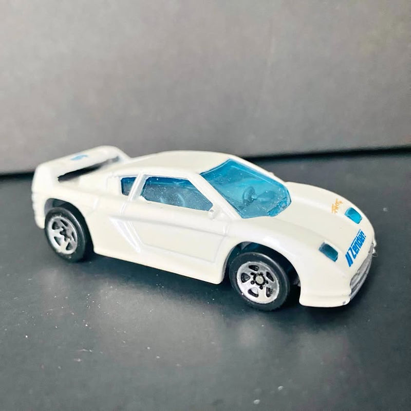 Vintage diecast collectible car with white body and blue windows