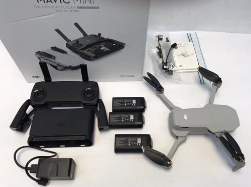 Grey quadcopter drone with controller, batteries, charging hub, and propellers