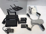 Grey quadcopter drone with controller, batteries, charging hub, and propellers