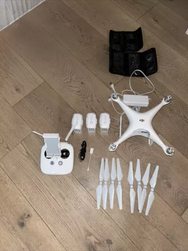 White quadcopter drone kit with controller, extra propellers, batteries and landing gear.