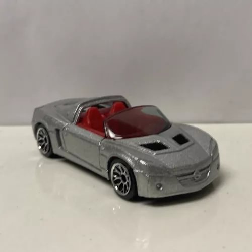Grey 1/64 scale diecast sports car model with black vents and red interior detail