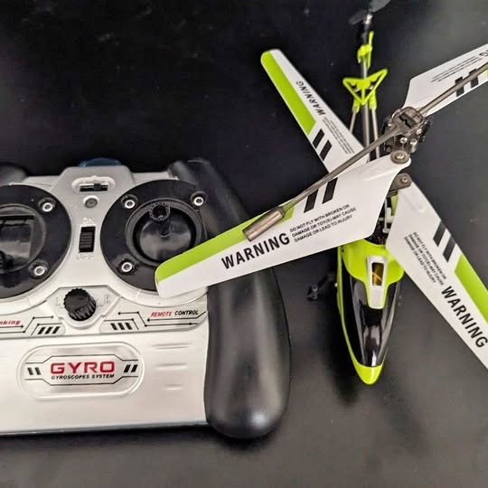 Gyro RC helicopter with white remote controller and lime blades, warning label