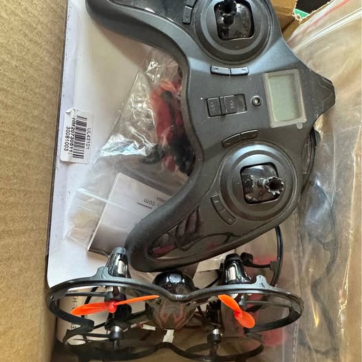 Gray quadcopter drone with orange propellers and circular camera housing