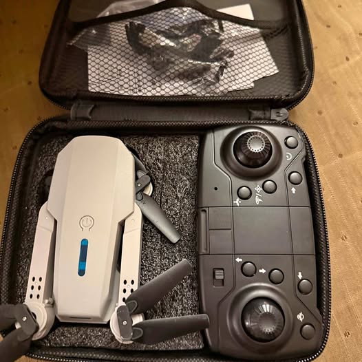 Foldable drone with gray remote controller inside a zippered carrying case