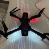 Black quadcopter drone with four propellers and red/white LED lights