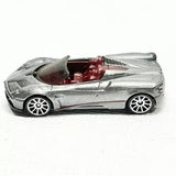 Silver 1/64 diecast roadster with open cockpit and red interior, detailed wheels