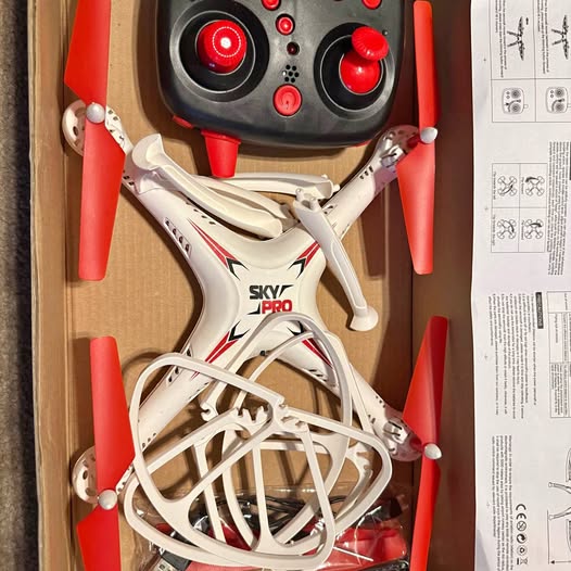 White toy drone with red propellers and protective frame, compact beginner model