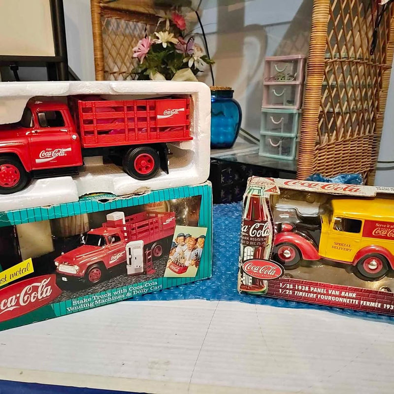 Red Coca-Cola diecast truck set in windowed display boxes, with two truck models