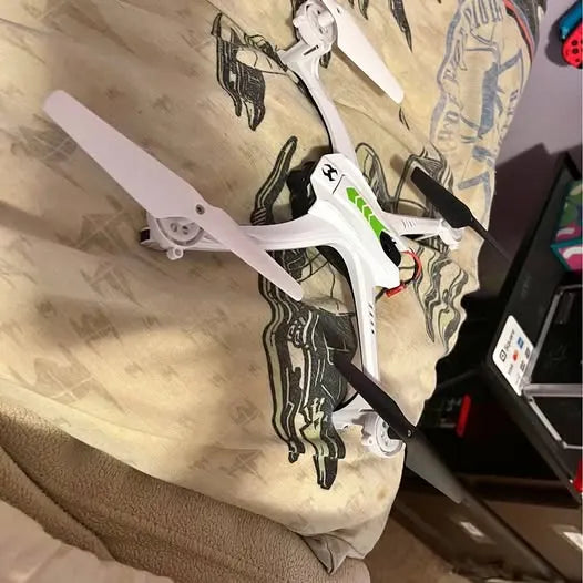 White quadcopter drone with green stripe and camera gimbal, four propellers visible
