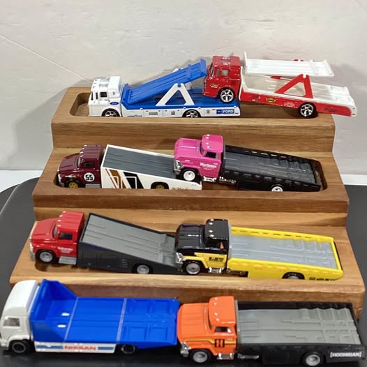 Diecast flatbed transport set with multiple toy trucks on a wooden display tray