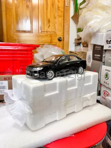 Black 1:18 scale diecast sedan model car, front three-quarter on white base
