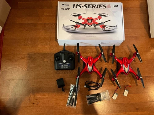 Red quadcopter drone kit with controller, extra batteries, and spare propellers