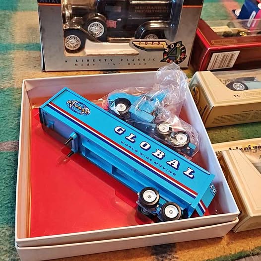 Blue diecast train model in box, with white wheels and clear plastic cover