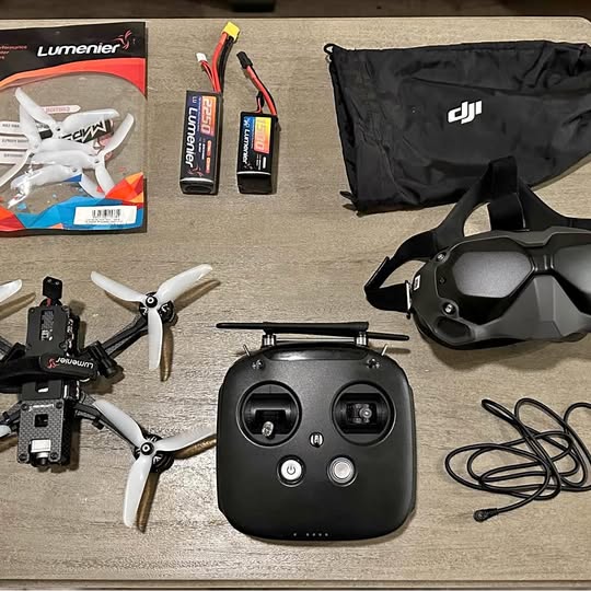 FPV drone kit with black controller, propeller drone, storage bag and cables