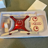 Red and white quadcopter drone in clear plastic box with propellers