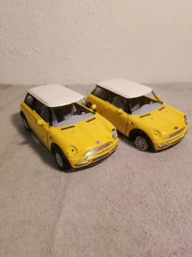 Pair of yellow diecast mini cooper toy cars, front angled view, two-door models