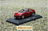 Red diecast model car on dark display base, detailed sedan with alloy wheels