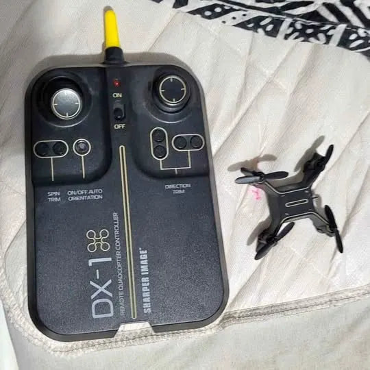 Drone controller with yellow antenna and black quadcopter with four propellers