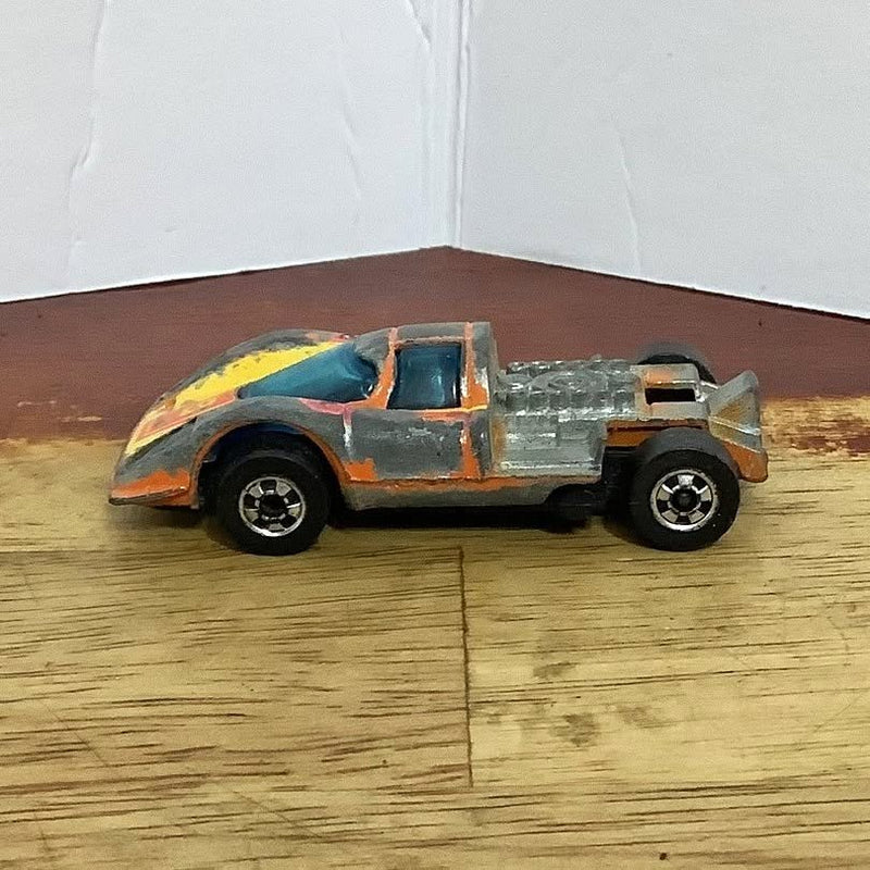 Hot Wheels diecast race car with gray body, orange and yellow decals, black wheels