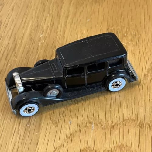 Black diecast model car with metal detailing and whitewall-style wheels