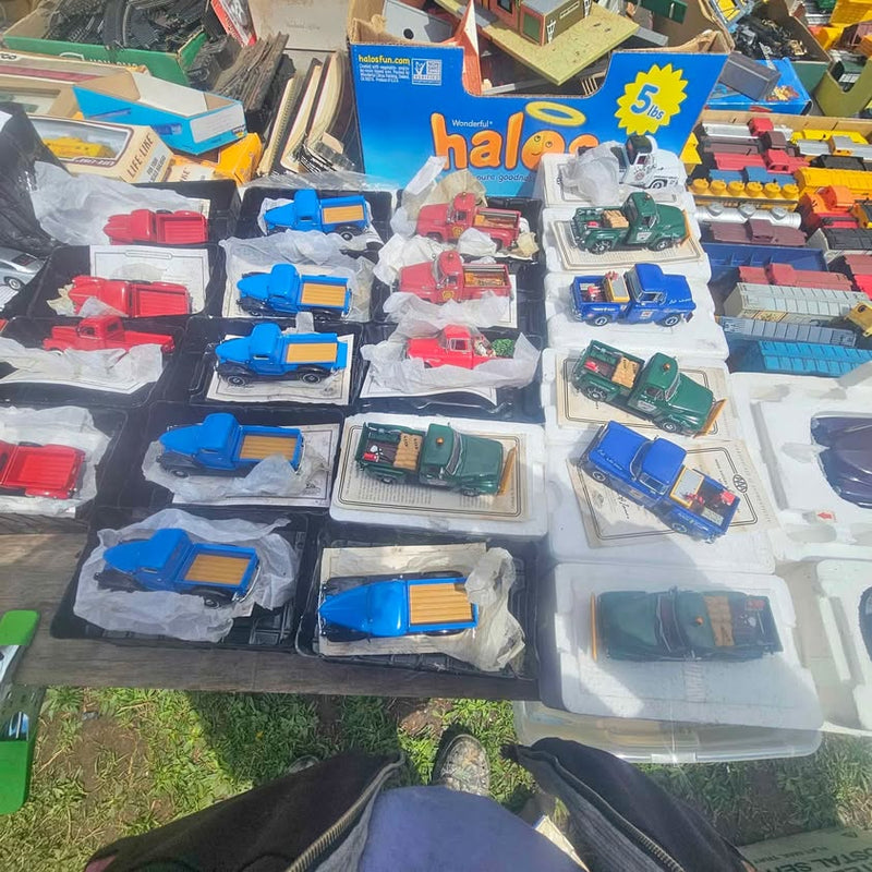 Diecast toy trucks in assorted colors, displayed in blister packs on a table