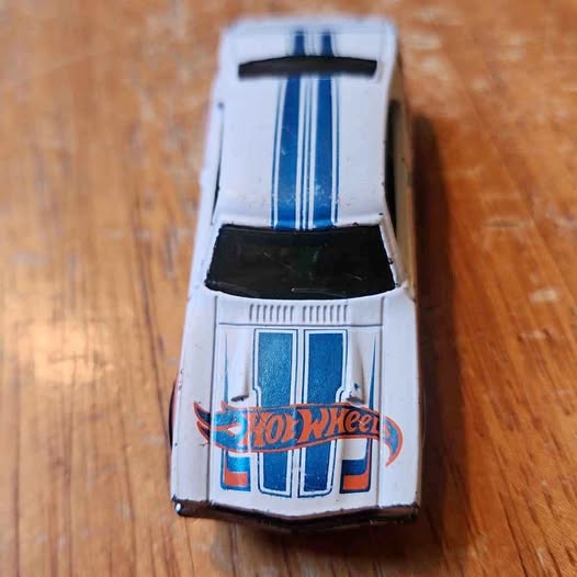 White and blue Hot Wheels diecast toy car with open hood detail.